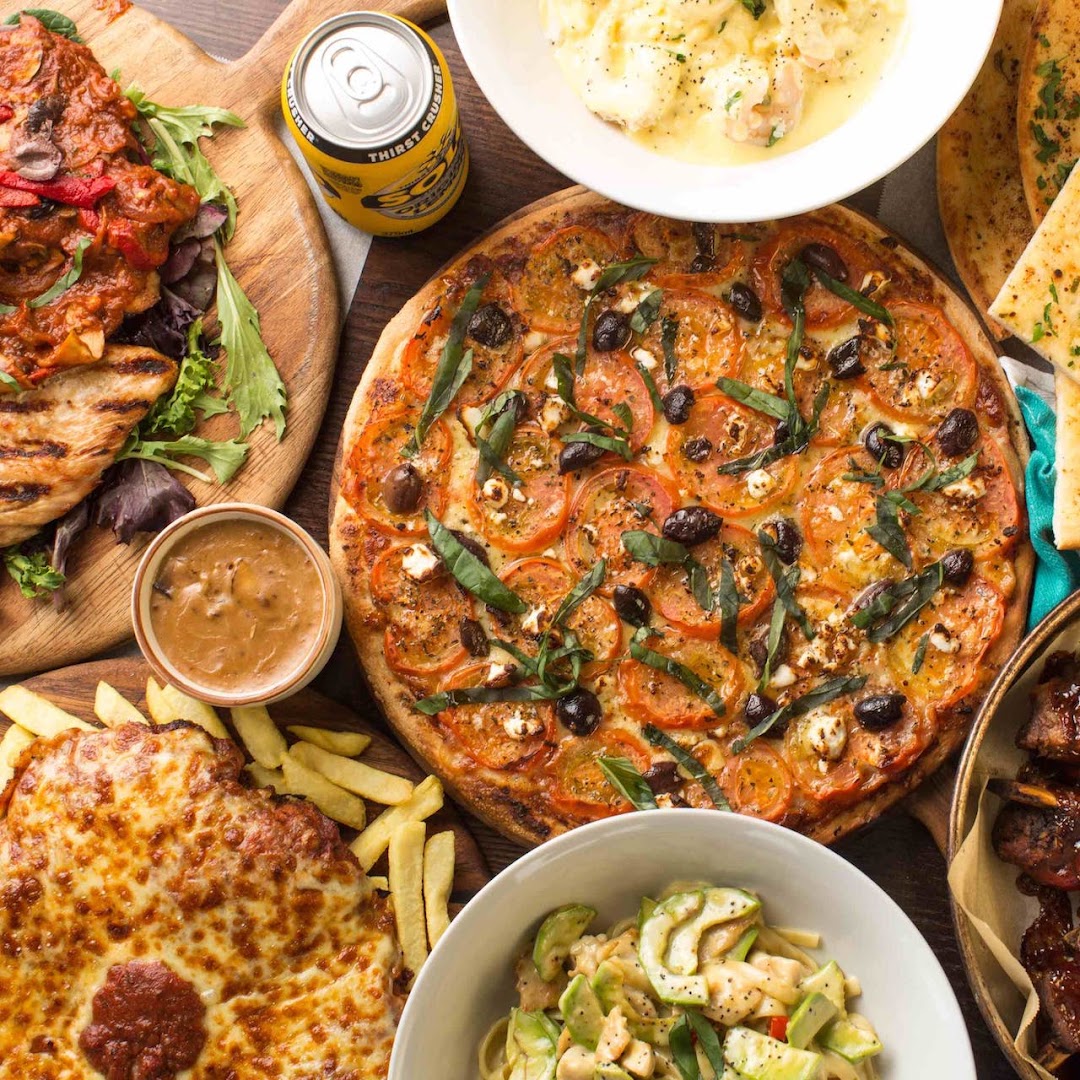 Overhead spread of La Romana's menu: tomato and olive pizza, chicken parmigiana, chips, ribs and pasta