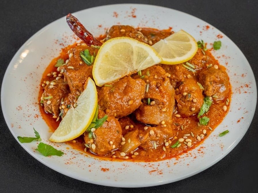 Plated curry with lemon, coriander and toasted spices on a white plate